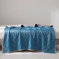 Dark Blue quilted summer blanket draped across a bed