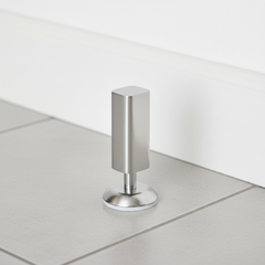 Silver magnetic floor door stop beside an open door