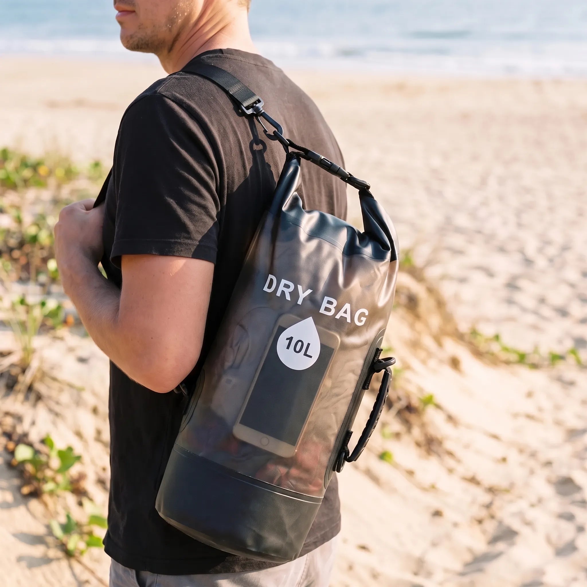 Black 10-liter roll-top dry bag carried on a beach
