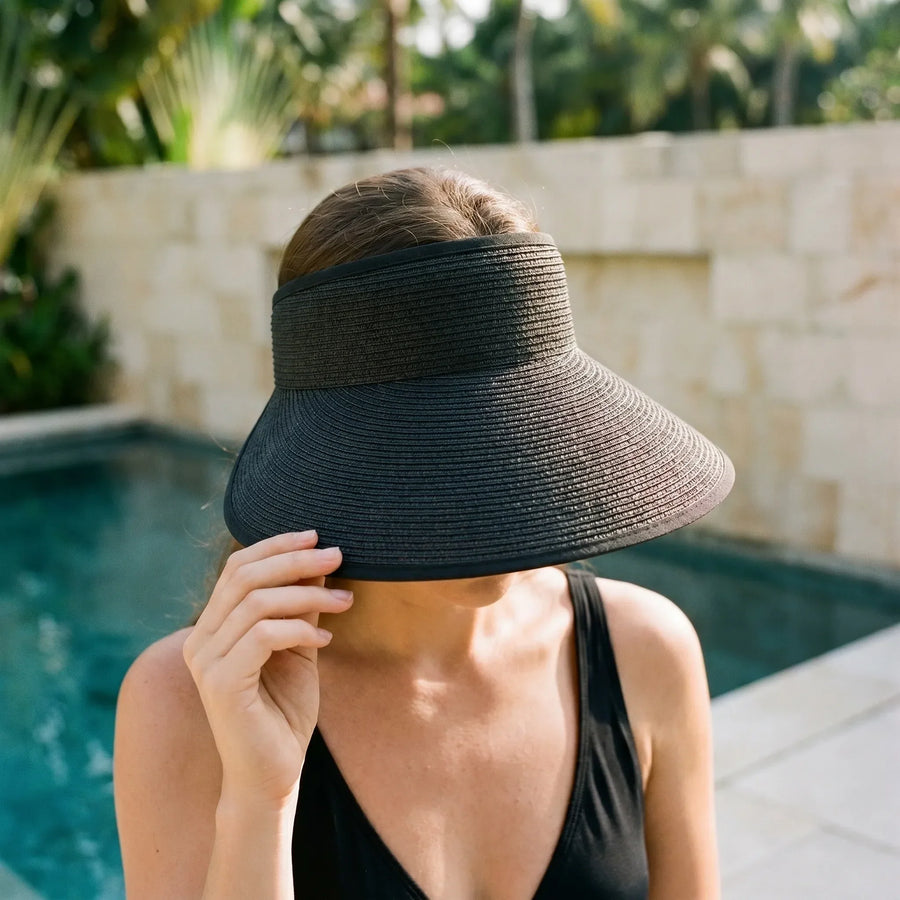 Black roll-up woven visor worn beside a pool