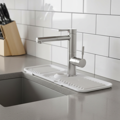 White silicone faucet splash mat around a kitchen faucet