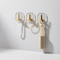 Three clear wall hooks holding small accessories
