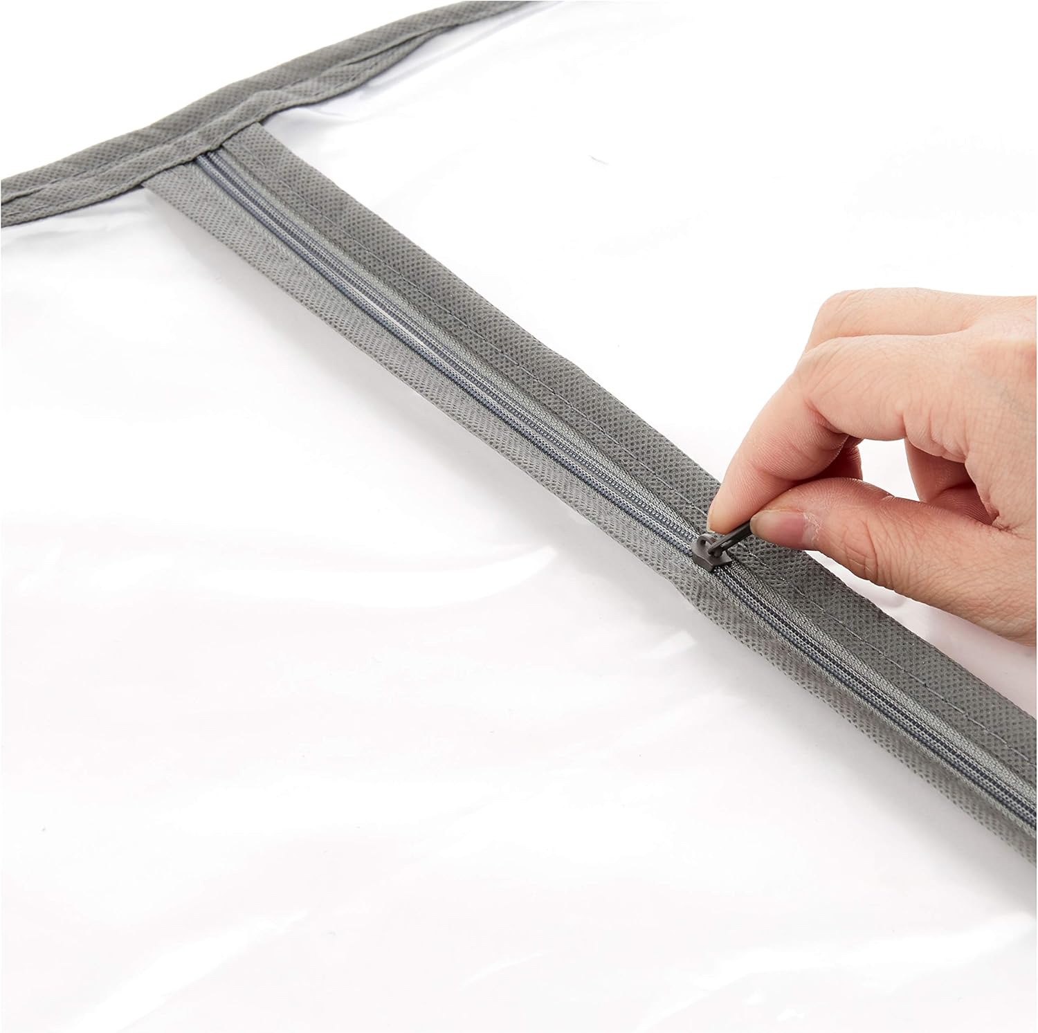 Hand opening the front zipper on a garment storage bag