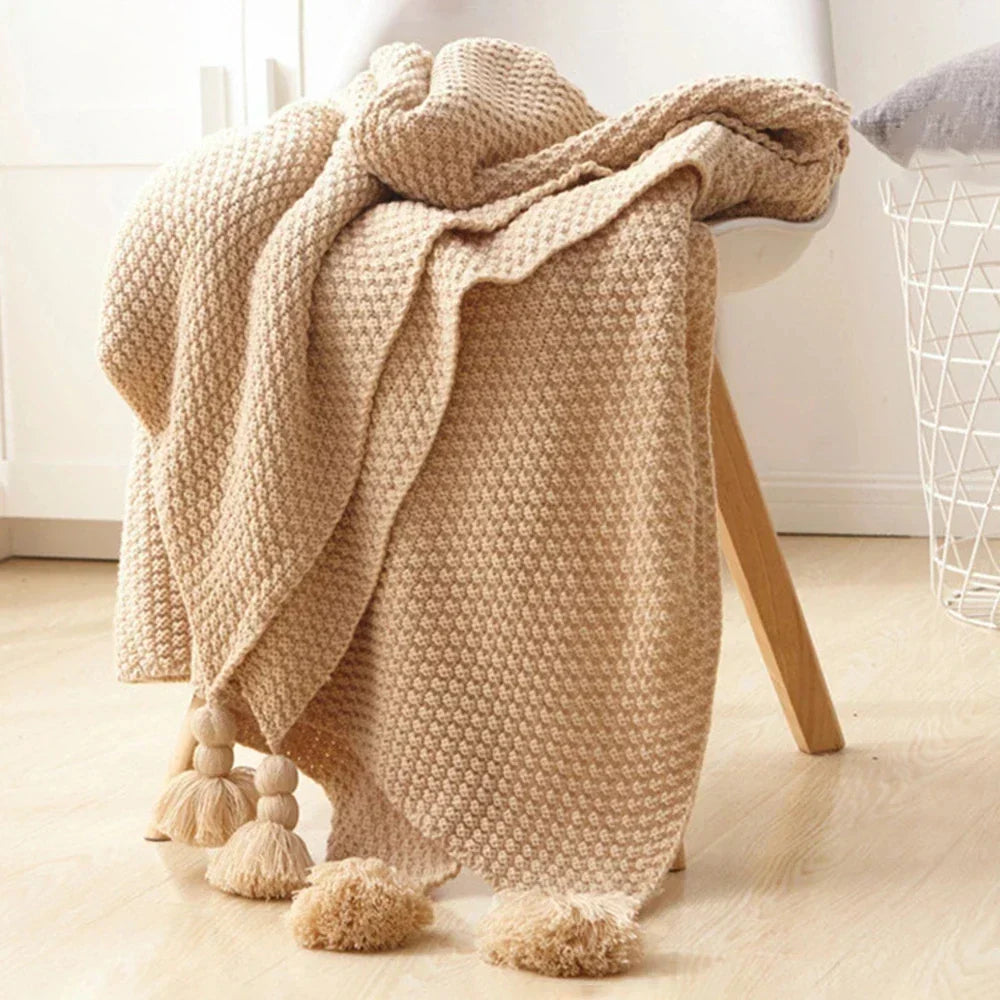Beige knitted tassel throw draped over a chair