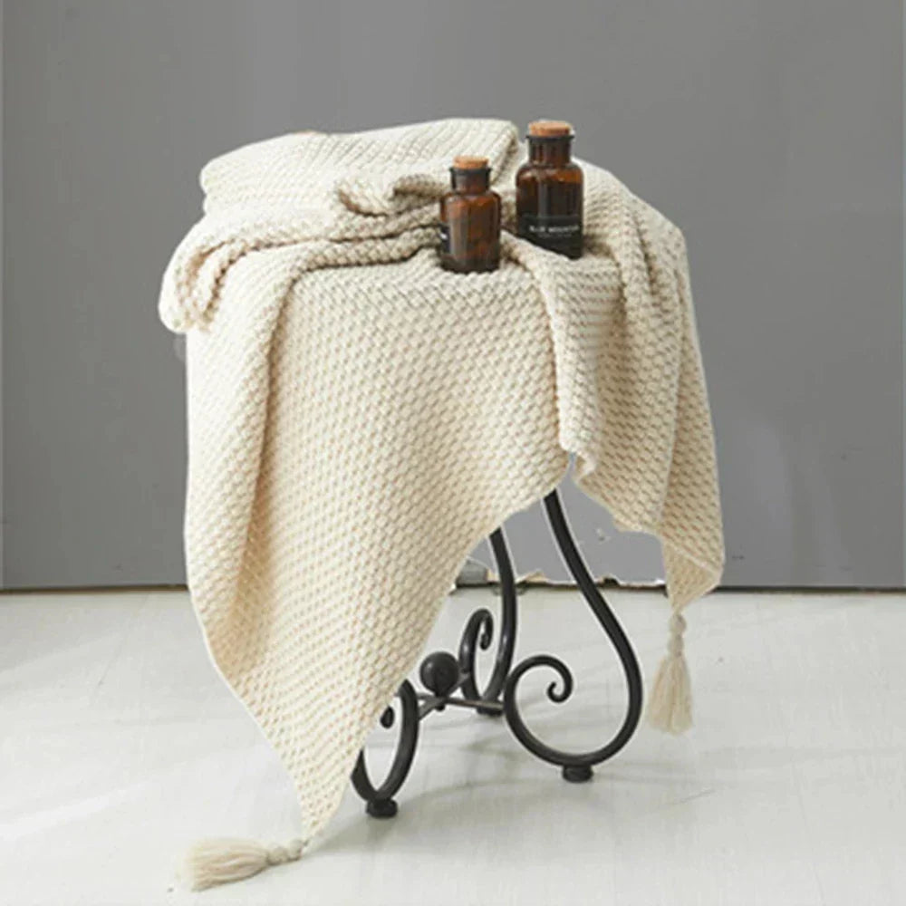 White knitted tassel throw draped over a small table