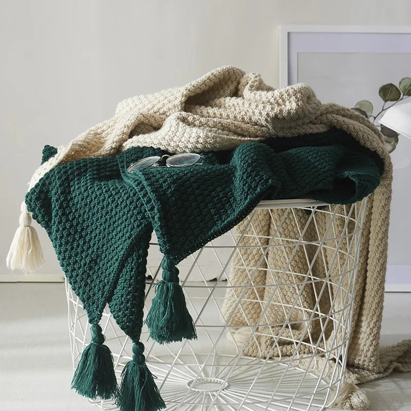 Deep Green knitted throw with tassels draped over a wire chair