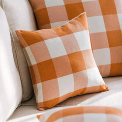 Orange plaid cushion covers layered on a sofa
