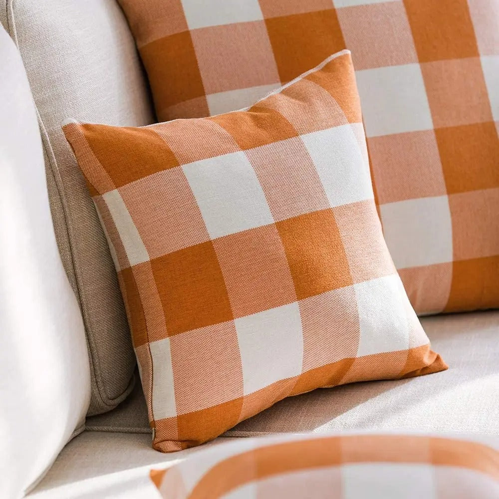Orange plaid cushion covers layered on a sofa
