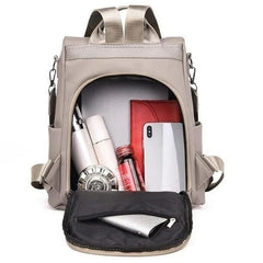 Open Khaki backpack with everyday items in the main compartment