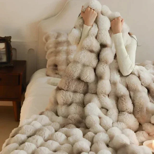 Light-neutral faux-fur throw held around a seated person