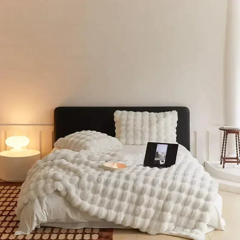 Light-neutral textured throw spread across a bed