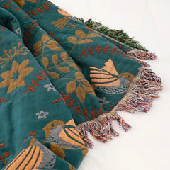 Folded Turquoise bird-pattern throw with fringe