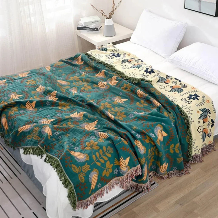 Turquoise-Beige reversible bird-pattern throw on a bed