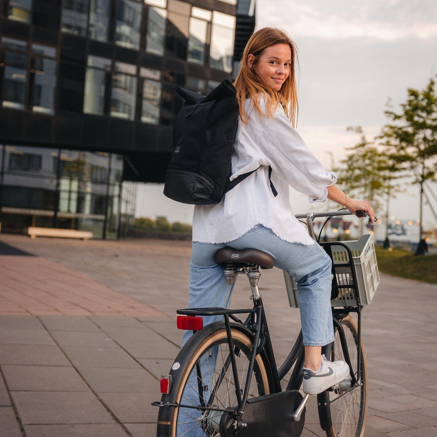 Black roll-top backpack worn while cycling