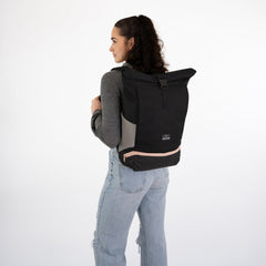 Black roll-top backpack worn in a studio setting